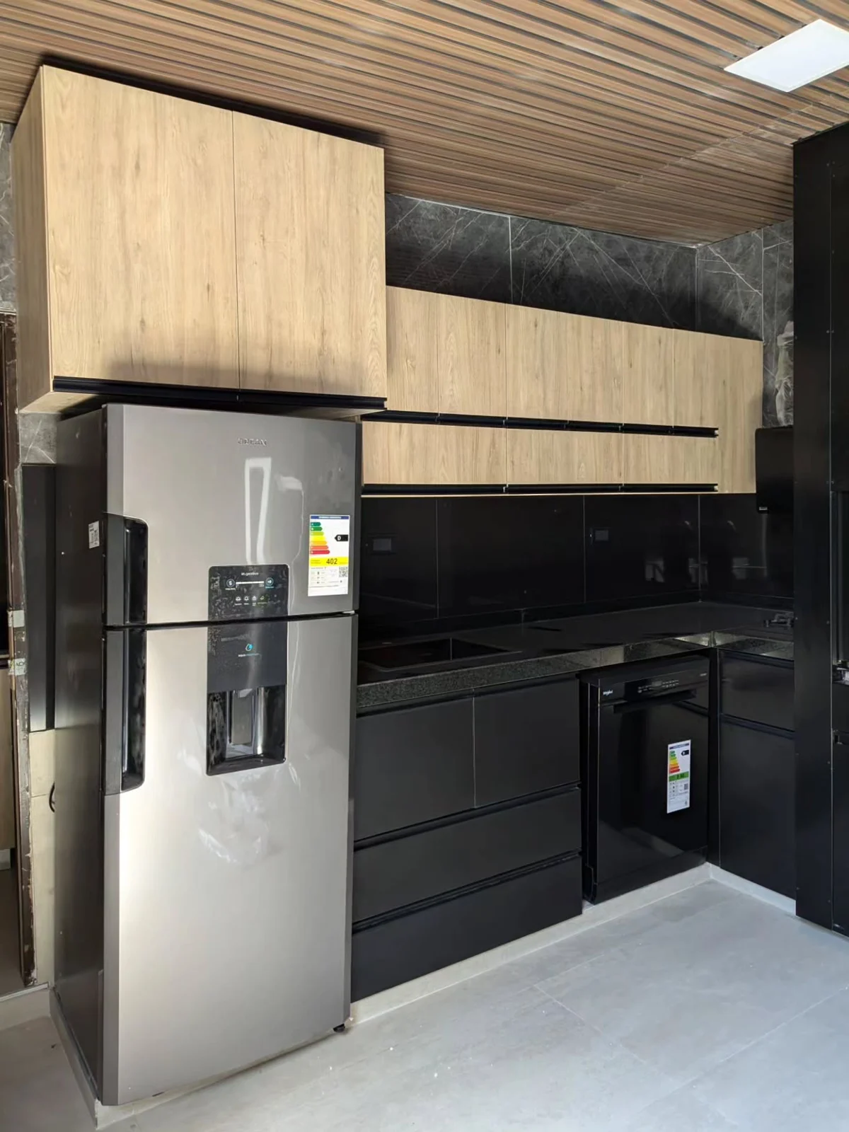 Cocina Kava con alacenas Cajú, muebles Negro Profundo y mesada de granito Negro Brasil